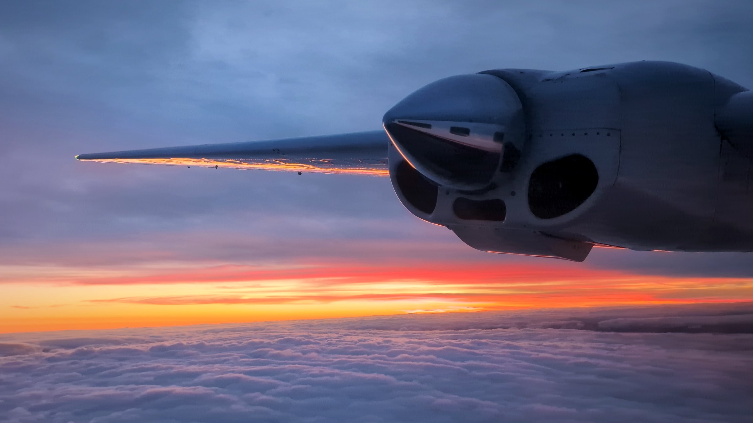 Looking out along the wing at the engine nacelle, sun setting below cloud