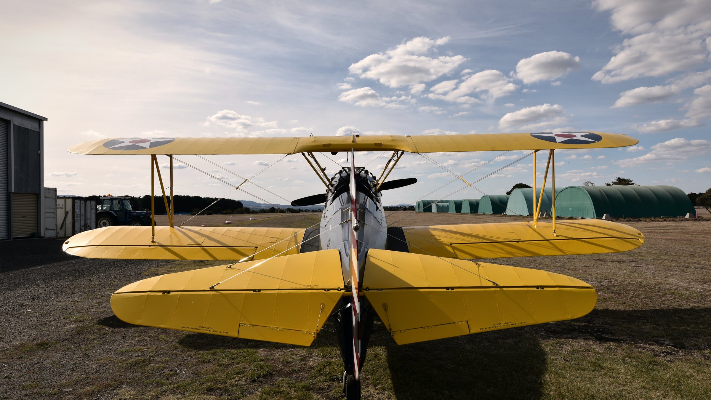A Boeing Stearman biplane viewed head-on from the tail, parked at the hangar